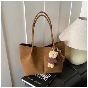 Brown faux suede tote bag with a small teddy bear charm and twin shoulder straps