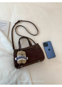 Dettaglio della borsa in pelle scamosciata caffè con ciondolo orsetto e tracolla