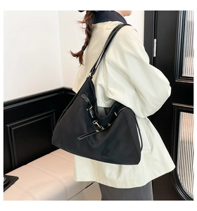 Black nylon tote bag with leather trim and adjustable shoulder strap worn by a model