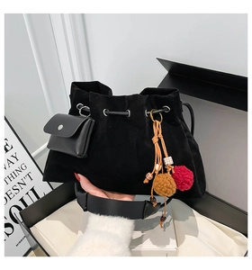 Close-up of black suede bucket bag featuring bohemian tassel and leather pouch detail