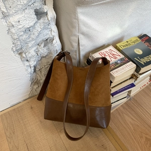 Detail of vintage brown bucket bag with suede and leather patchwork near antique books