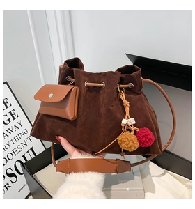 Detail of vintage brown suede bucket bag featuring drawstring closure and tassel charm