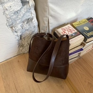 Detail of dark brown bucket bag with mixed matte suede and smooth leather textures