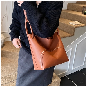 Detail of caramel leather bucket bag with contrast white stitching and ring handle loop