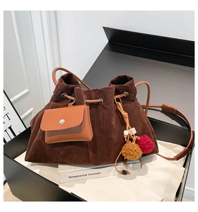 Detail of dark brown suede drawstring bucket bag with a leather pouch and colorful charms