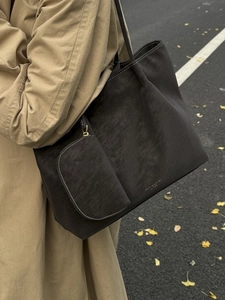 Grand sac cabas en cuir noir avec pochette porté à l'épaule dans un décor d'automne