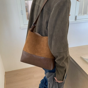 Detail of retro bucket bag showing textured suede and smooth leather splicing with strap