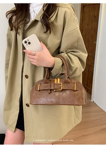 Brown vintage leather shell bag with gold buckle detail worn with beige trench coat