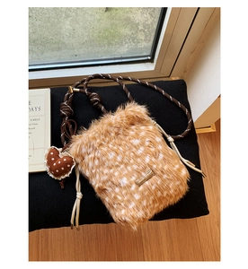 Detailaufnahme der Kunstpelz-Tasche mit Rehkitz-Muster, Herzanhänger und gewebtem Gurt