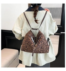 Detailed view of leopard print tote bag with brown leather straps on model's shoulder