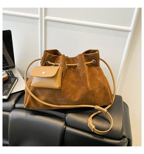 Detail of a brown suede drawstring bucket bag with a mini pouch and long shoulder straps