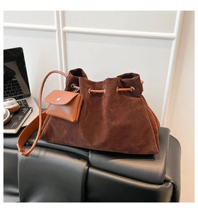 Detail of dark brown faux suede drawstring bucket bag with a small coin purse on a bench