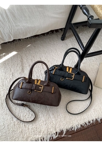 Detail of retro leather Boston bags in brown and black with elegant gold hardware