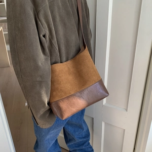 Detail of a two-tone tote bag with camel suede and dark brown faux leather texture