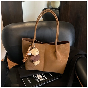 Close-up of vintage brown suede tote bag featuring a cute beige teddy bear charm