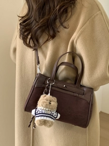 Borsa a tracolla vintage marrone con ciondolo a orsetto indossata da una modella