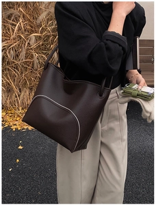 Close-up of deep brown lychee grain leather tote bag with elegant curved stitching detail