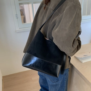 Detail of minimalist black mixed-texture shoulder bag with matte and glossy finish