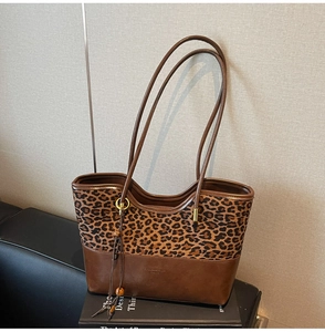Detail of leopard print patchwork tote bag with stylish fringe charm and leather strap