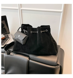 Detail of black suede bucket bag featuring drawstring closure and silver eyelets
