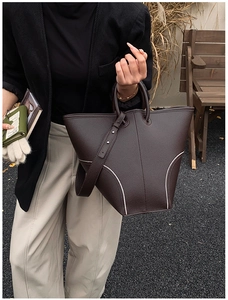 Detail of dark brown lychee leather bucket bag with contrast stitching and sturdy handles