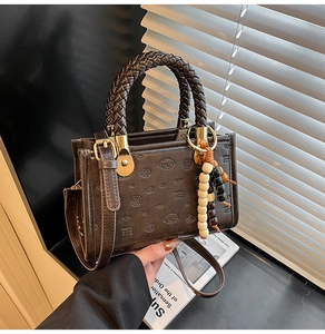 Close-up of brown leather crossbody bag with embossed bears and braided rope handle