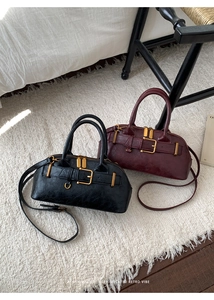 Detailed shot of retro faux leather handbags in black and burgundy on a white rug