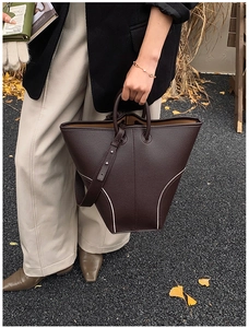 Close-up of deep brown lychee grain leather bucket bag with white contrast stitching details
