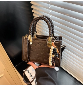 Detail of dark brown leather handbag with puppy embossing and woven handle