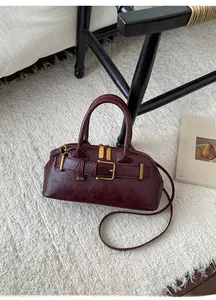 Close-up of a burgundy leather Boston bag with metallic buckle and vintage brass hardware