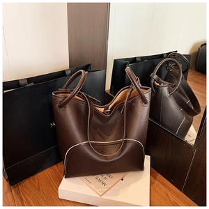 Detailed close-up of a dark brown pebble leather tote bag with white decorative stitching