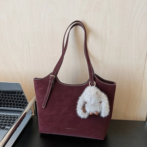 Detail der weinroten Shopper-Tasche mit weißen Kontrastnähten und Plüsch-Hasen-Anhänger