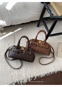 Detail of two vintage-style leather Boston bags in dark and light brown with gold buckles