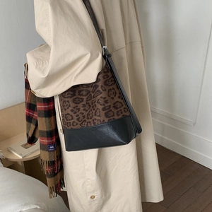 Fashionable leopard print bucket bag with black leather base worn with a trench coat