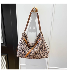 Close-up of leopard print canvas tote bag with brown leather strap and buckle detail