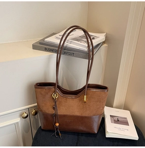 Detail of dark brown tote bag showing mixed suede and leather texture with golden logo