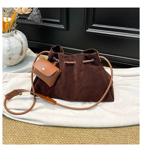 Detail of dark brown faux suede bucket bag with drawstring and leather card holder pouch
