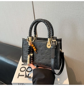 Detail of black leather handbag with embossed cartoon pattern and woven handle