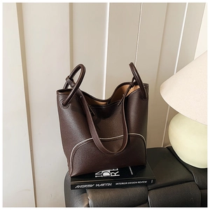 Close-up of dark brown leather bucket bag with white contrast stitching and pebble texture