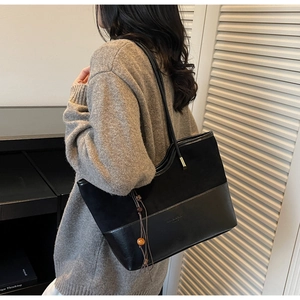 Detail of black patchwork tote bag with suede finish and wooden bead tassel decoration