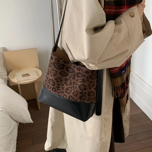 Detail of leopard print tote bag with matte black leather panel and shoulder strap