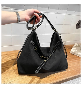 Close-up of black suede tote bag with shiny leather trim and vintage gold hardware