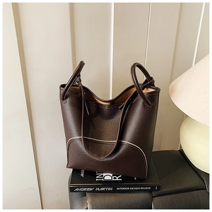 Detail of dark brown leather bucket bag with contrast stitching and dual handle design