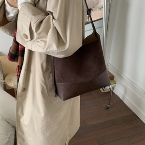 Detail of dark brown suede and smooth leather bucket bag shown on model shoulder
