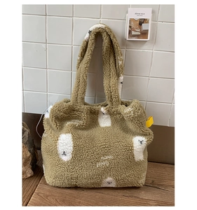 Dettaglio della borsa tote in peluche marrone con motivi di agnello e etichetta gialla