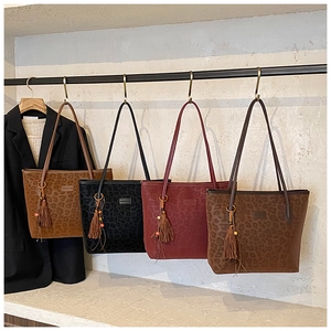 Detail view of four leopard print tote bags in brown, black, and burgundy with beaded tassels