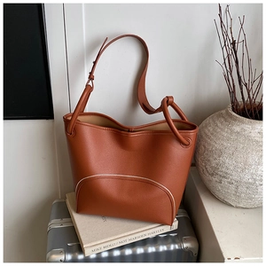 Detail of caramel brown leather bucket bag with white contrast stitching on vintage suitcase