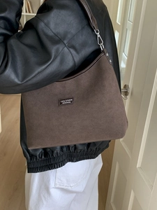 Brown suede underarm shoulder bag with leather straps on a model in leather jacket