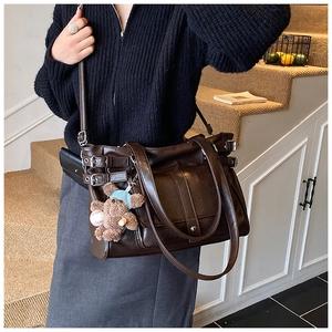 Brown vintage faux leather tote bag with stylish buckle details worn on a staircase
