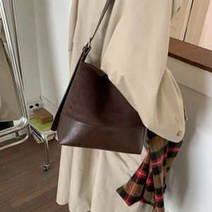 Detail of dark brown matte leather bucket bag paired with a stylish beige trench coat